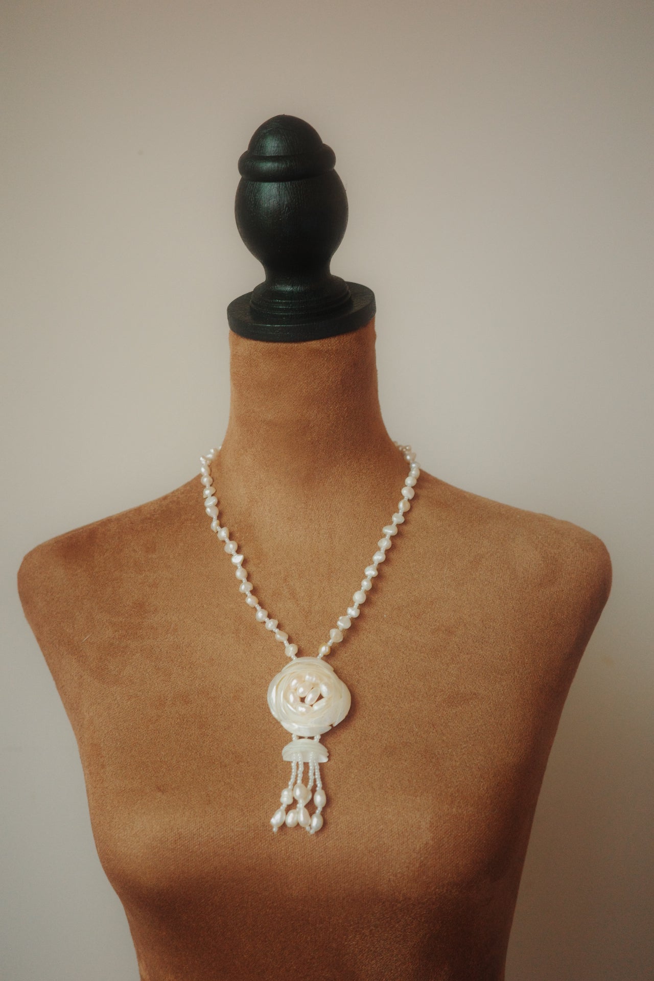 Pearl necklace on a mannequin bust with a plain background