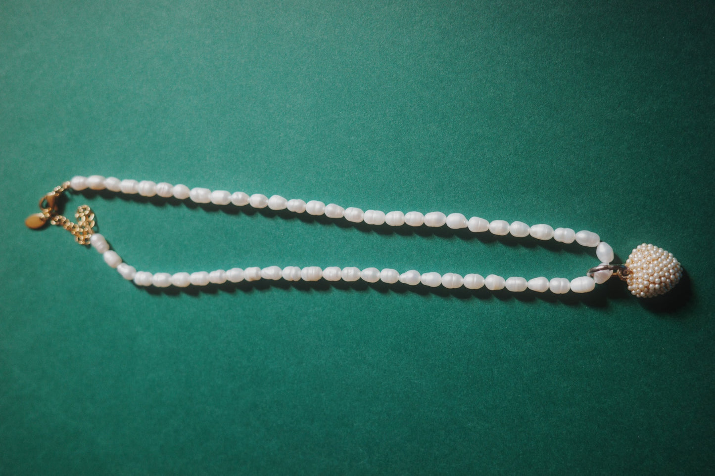 Pearl necklace with gold clasp on a green background