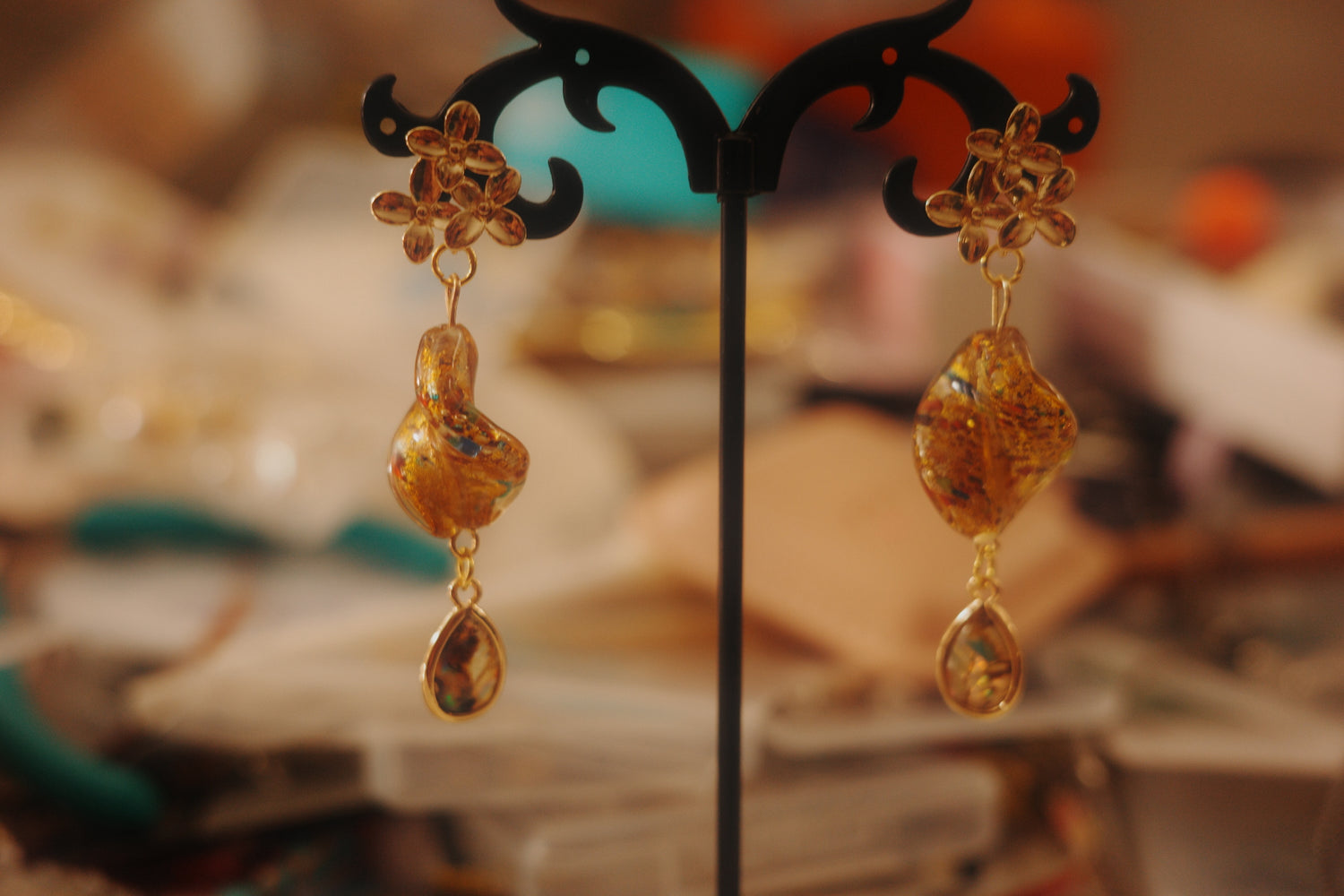 Pair of gold earrings on a black stand with a blurred background