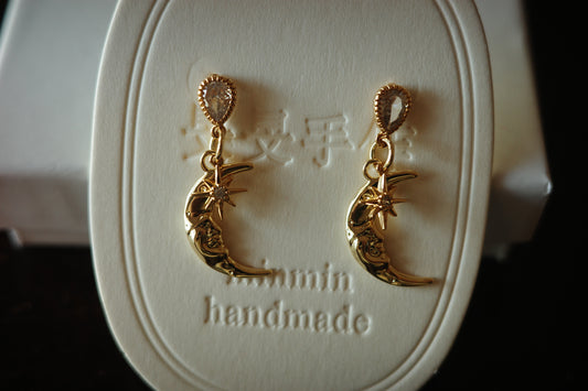 Gold-plated crescent moon and star earrings on model with lace top, soft golden lighting, celestial jewelry by MinMin Handmade.